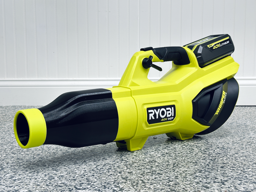 A yellow and black Ryobi 40V HP cordless leaf blower with a STUBBY® Car Drying Nozzle for RYOBI 730, 650, & 600 CFM Leaf Blowers sits on a speckled gray floor against a white paneled wall.