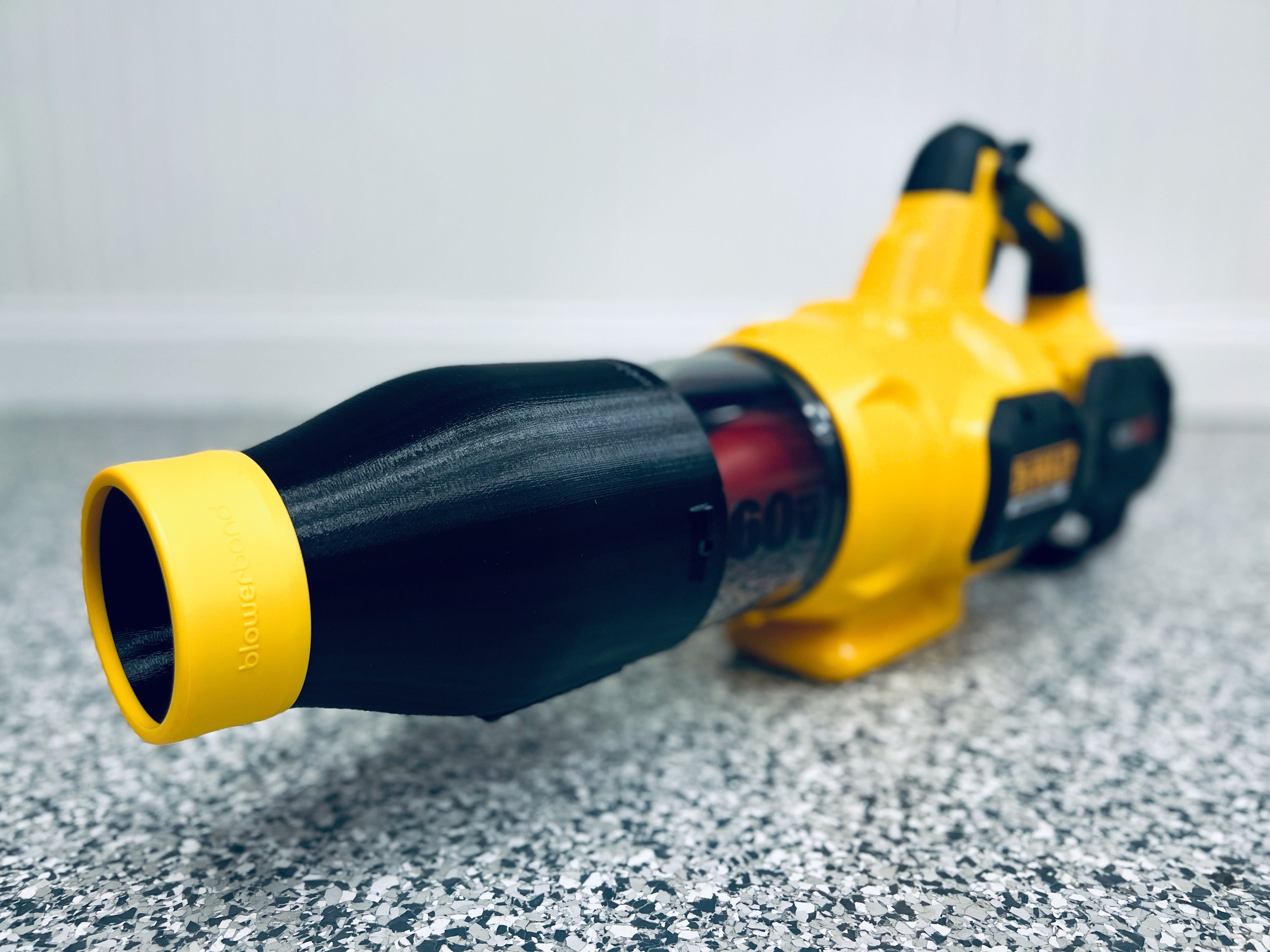 A STUBBY® Car Drying Nozzle for DEWALT 60V MAX Leaf Blowers (DCBL772B & DCBL777B) sits on a speckled gray floor by a white wall—a perfect car drying accessory for your garage.