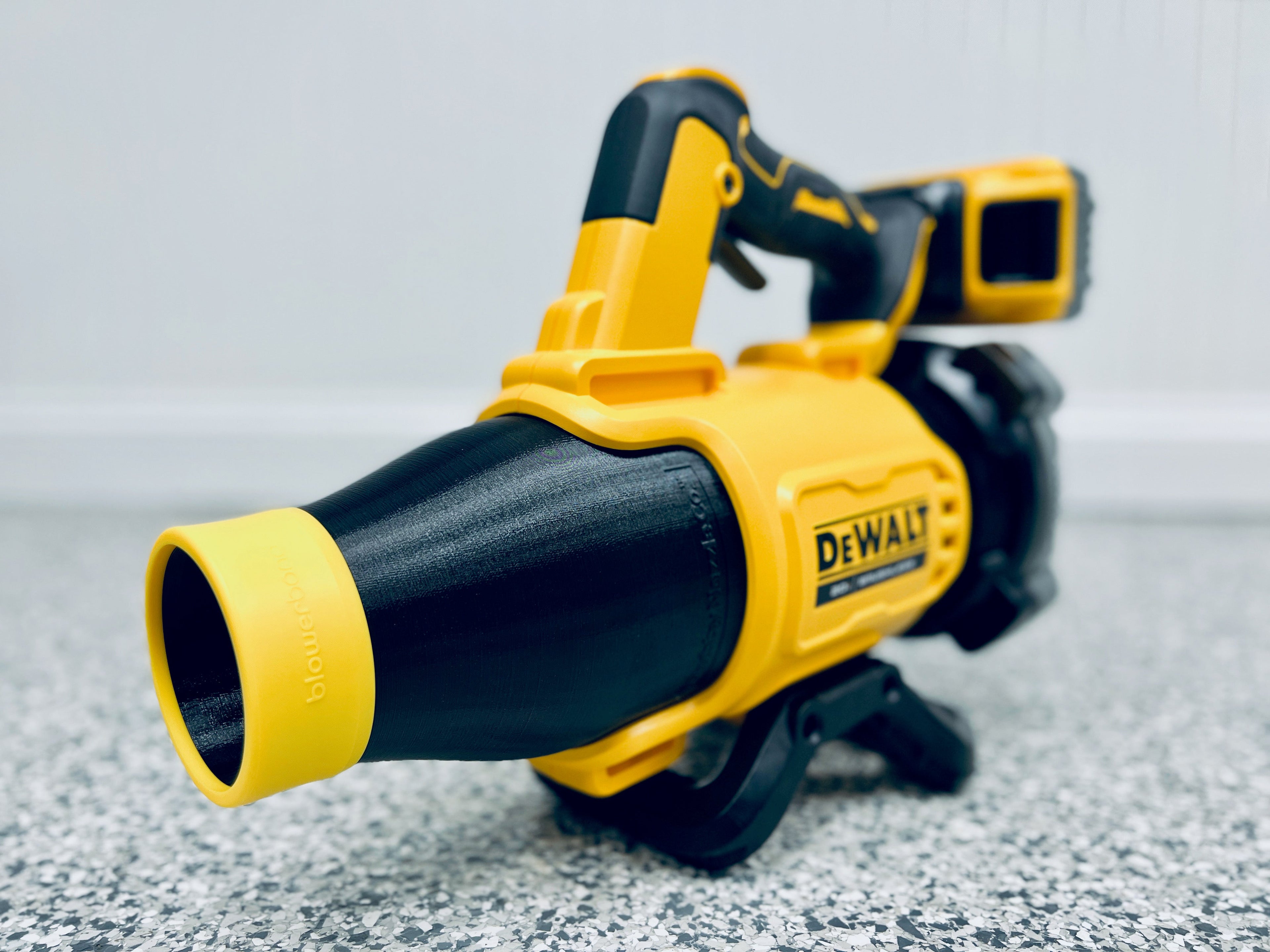 A STUBBY® Car Drying Nozzle is attached to a yellow and black DEWALT 20V MAX XR Leaf Blower (DCBL722B) with a silicone Blowerband, resting on a speckled gray floor, viewed from the front with the brand label visible.