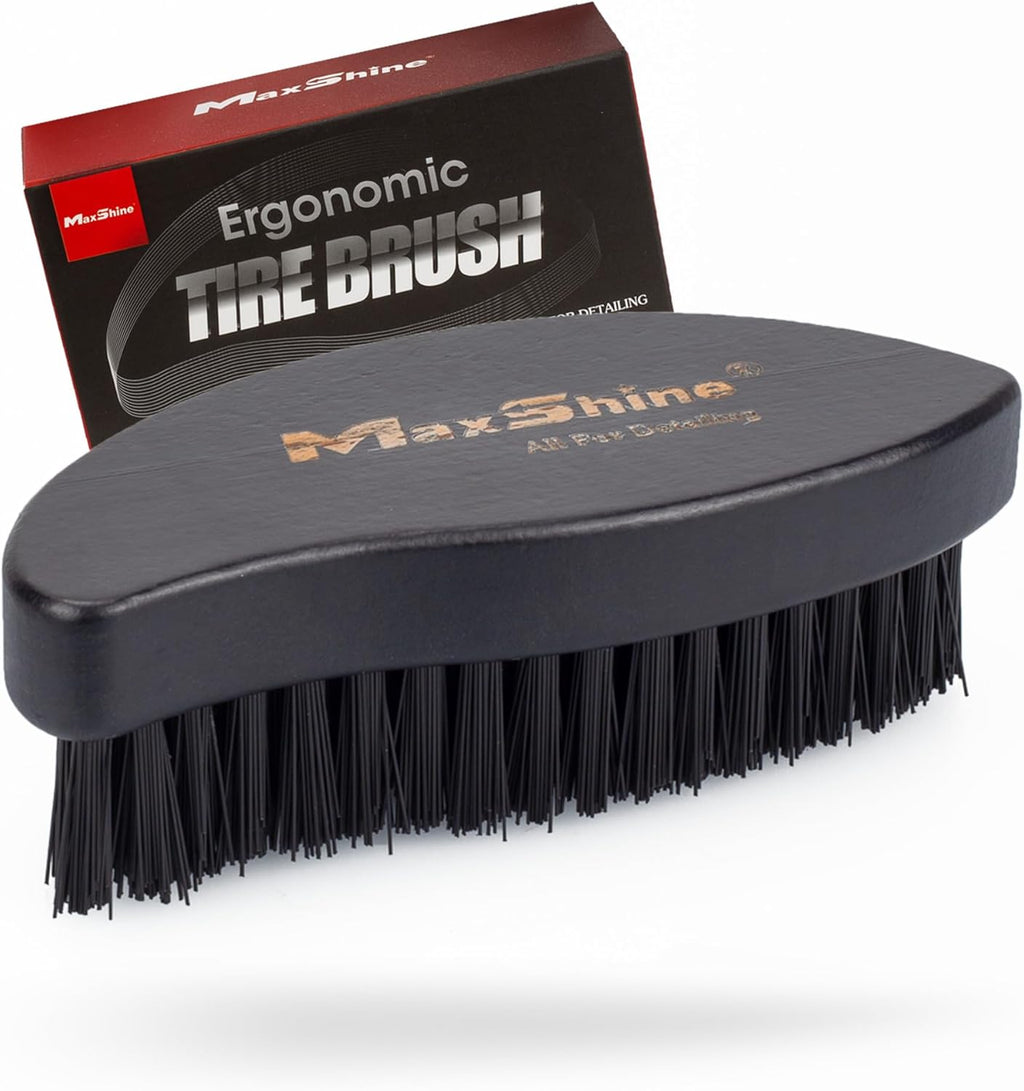 The MaxShine Ergonomic Tire Cleaning Brush features thick black bristles and a curved black handle, displayed before its box labeled “Ergonomic Tire Cleaning Brush” in bold letters.