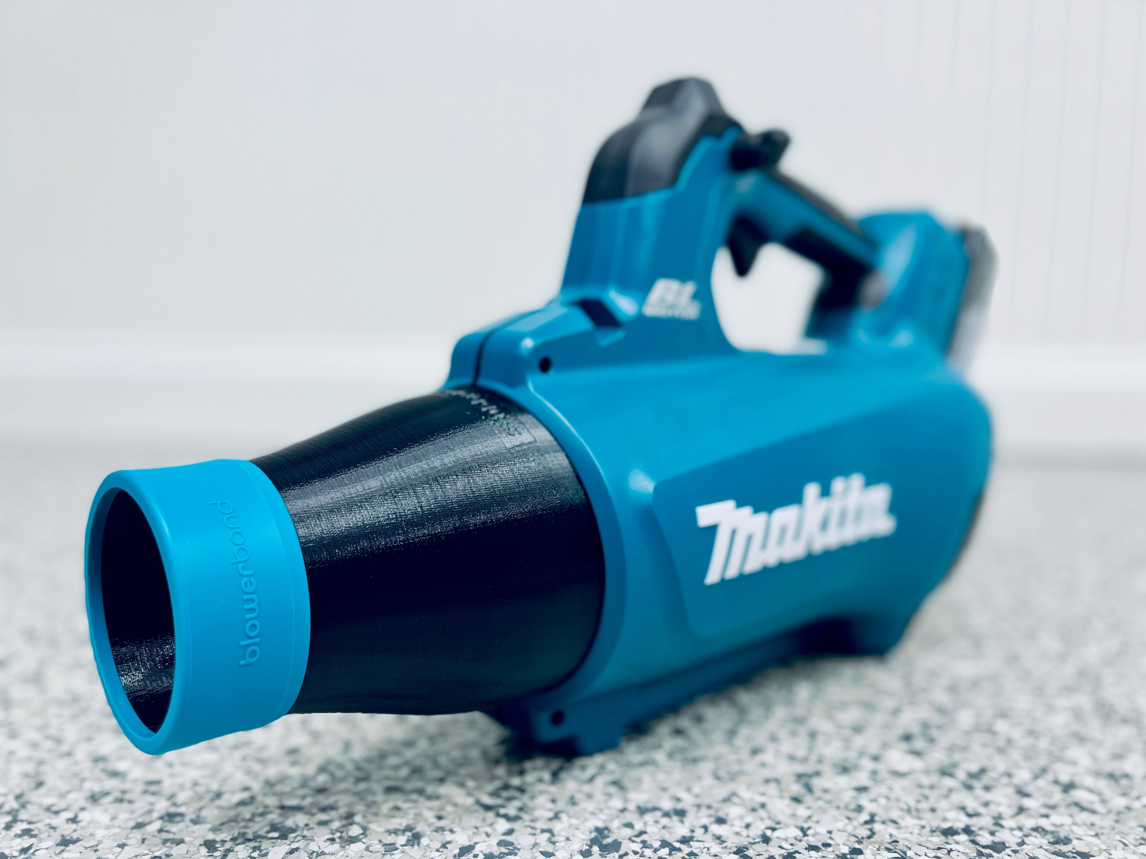 A STUBBY® Car Drying Nozzle for Makita 18V LXT Leaf Blower (XBU03Z & DUB184Z) sits on a speckled floor near the camera, its branding visible—a practical garage accessory for car drying.