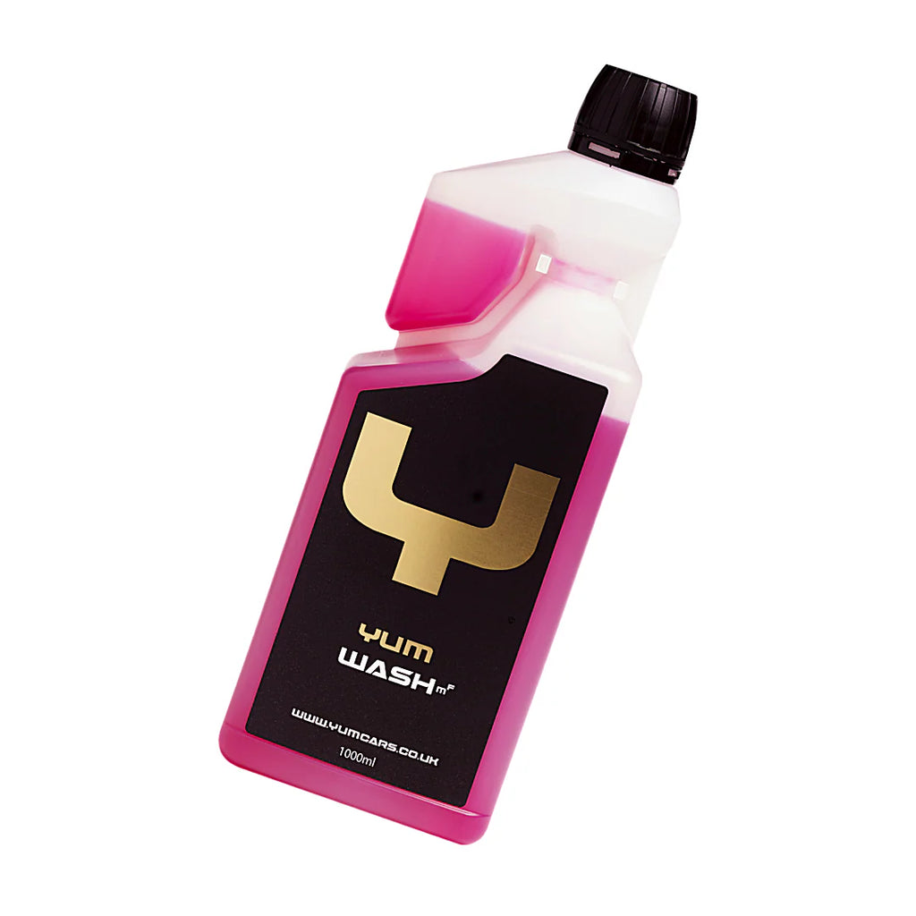 A tilted bottle of Yum Wash MF 1,000ml with pink liquid, black cap, and a black and gold label. Ideal for deep cleaning your favorite microfiber towels.